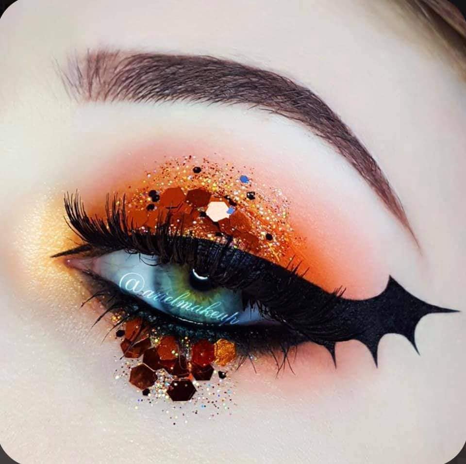 17 Maquillaje Halloween Parpados tipo alas de murcielago negro parpados Naranjas con sombos brillantes dorados y purpurina