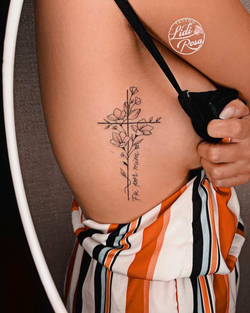 7 Artista Lidi Rosa Tattoo Cruz con Flores negras y hojas en el costado del pecho con frase Foi por mim Era para mi