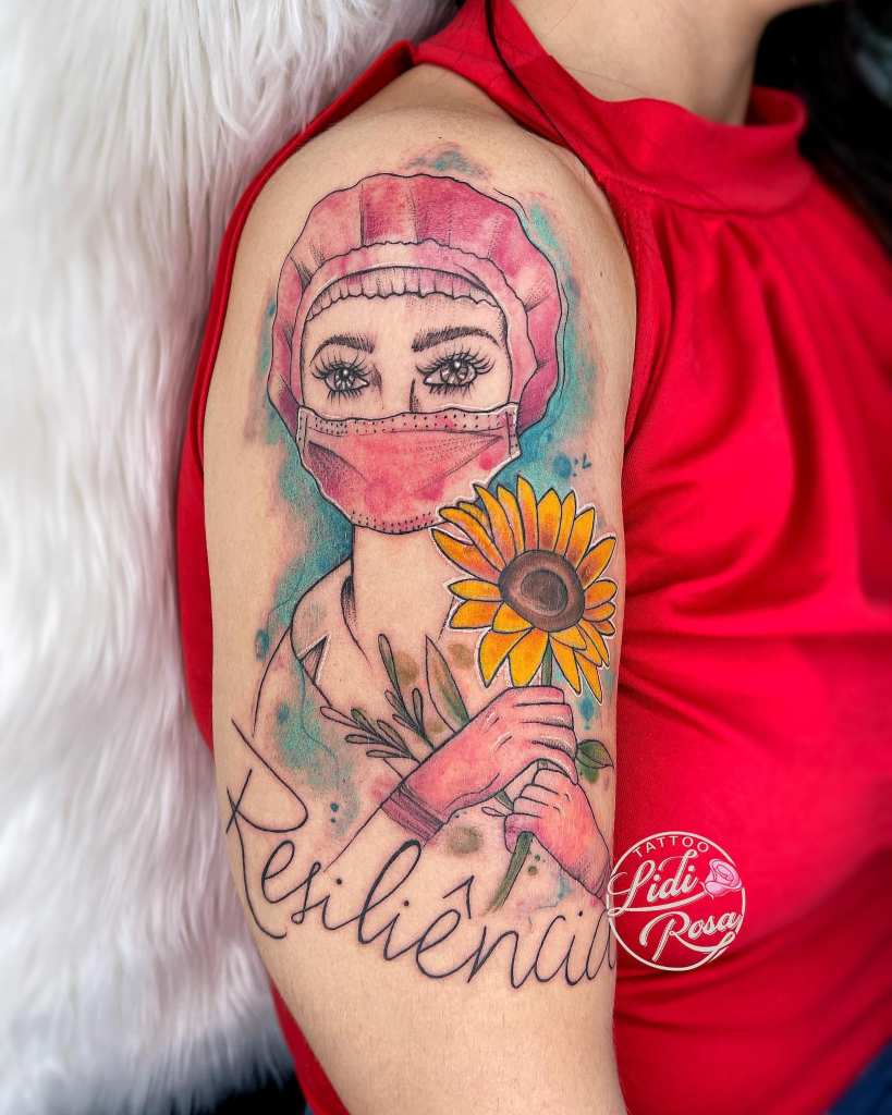 8 Artista Lidi Rosa Tattoo Donna Infermiera con maschera rossa, guanti e berretto tra i capelli e con un girasole arancione sul braccio con la parola Resilienza
