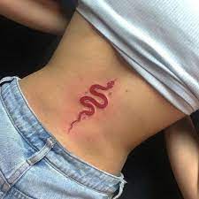 Tattoos mit roter Tinte, kleine Schlange auf dem unteren Rücken in der Wirbelsäule