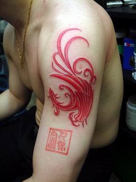 Tatuaggi con pesci Koi con inchiostro rosso con una coda molto lunga sul bicipite del braccio dell'uomo