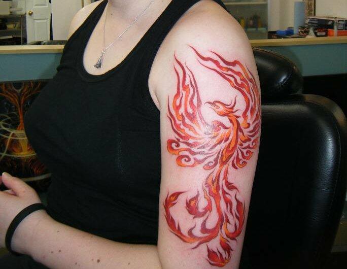 Tatuajes con Tinta Roja ave feniz en brazo conbinado con naranja