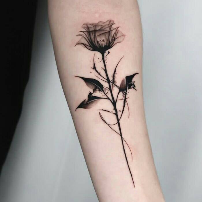 106 schwarze verschwommene Tattoos. Blume mit Blättern und Stiel mit Linien und Kurven auf dem Unterarm