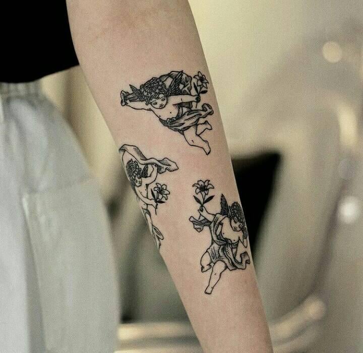 12 schwarze Tattoos. Drei kleine Engel auf dem Unterarm mit Blumen in den Händen