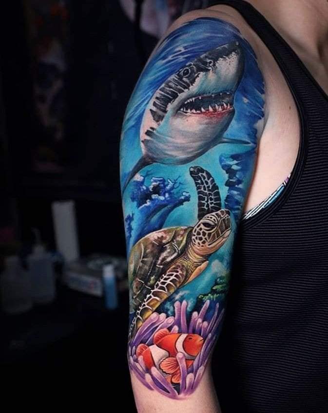 19 Tatuagem realista representando o fundo do mar com tartaruga marinha, tubarão, peixe laranja de Nemo, algas corais e água no braço