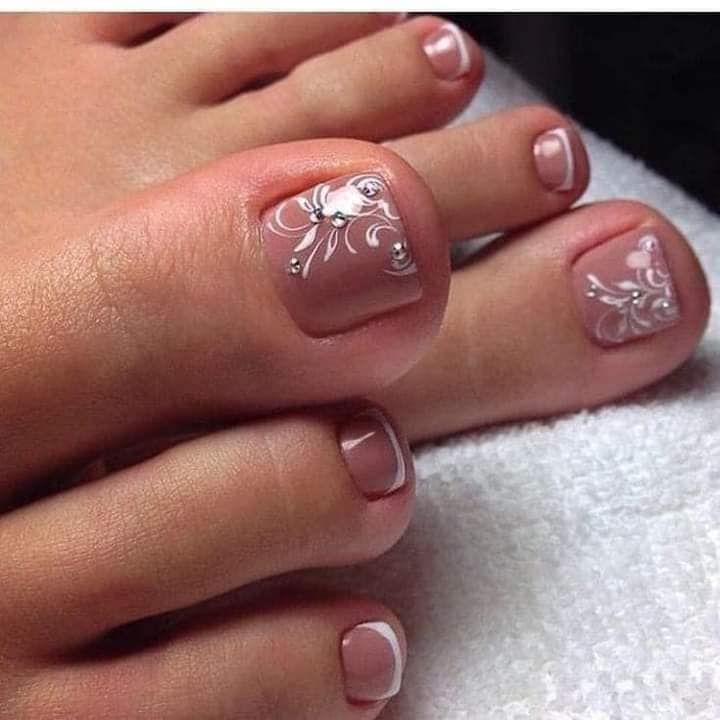 105 Nageldesigns für Füße mit rosa Haut mit Ornamenten in Form von weißen Blumen und silbernen Steinen