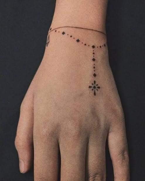 62 Tatuajes de Rosarios con pequena pulsera de trazo fino y detalle de cruz geometrica en la mano