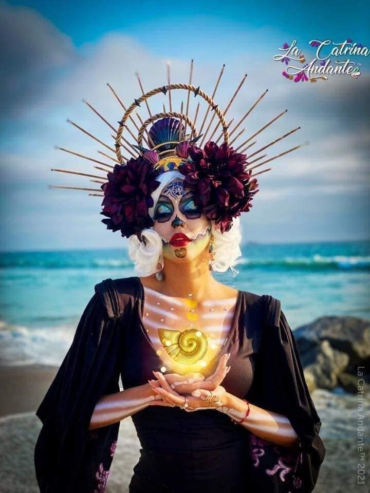 11 La Catrina-Kostüme, einfaches Make-up mit Symbolen und Details in Blau, großes und hohes Stirnband mit violetten Blumen, violettes Kleid mit Ausschnitt auf der Brust, Skelett am Körper