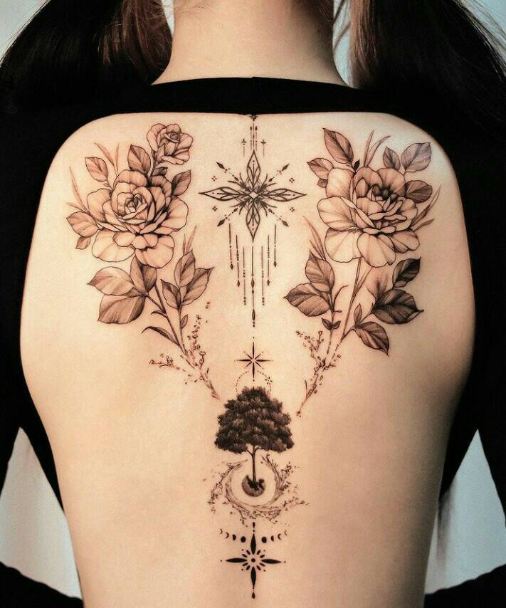 117 hermoso tatuaje floral en la espalda de una mujer con un arbol que tiene una estrella abajo