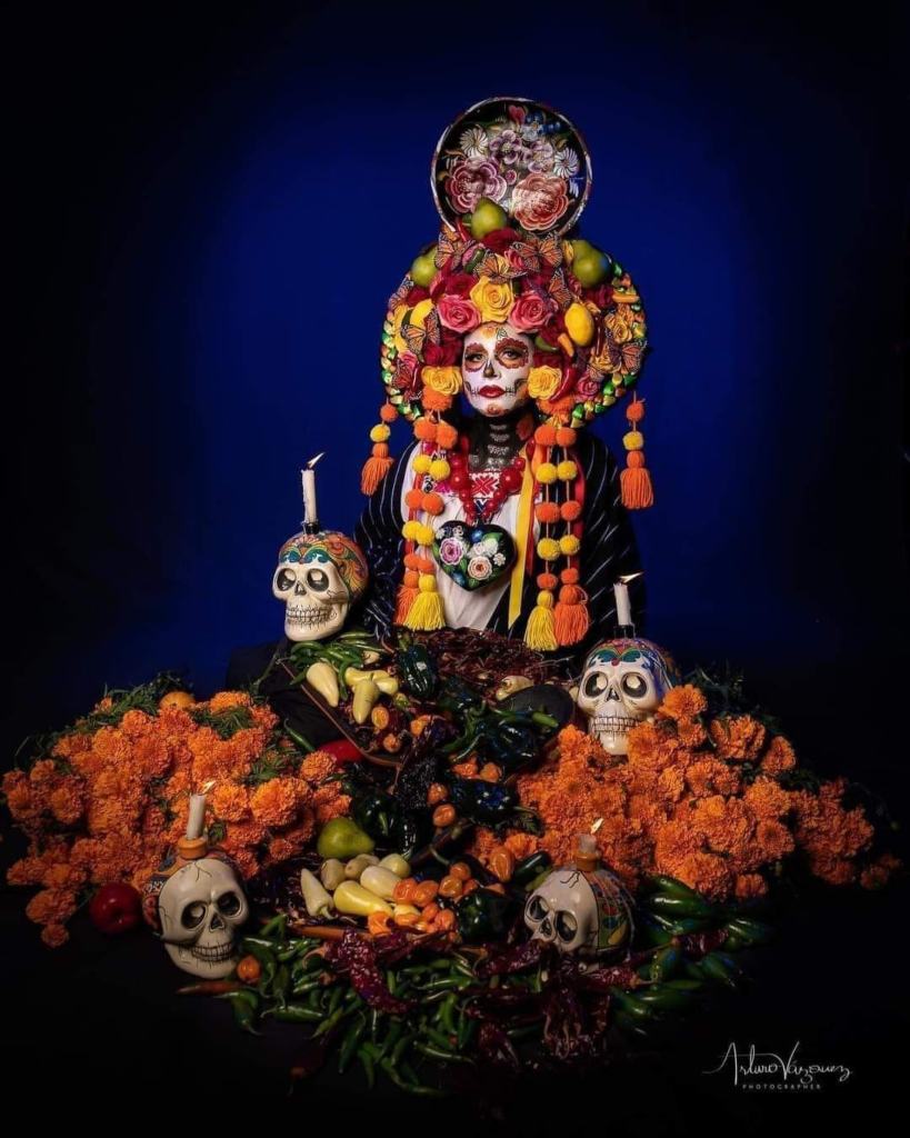 13 Disfraces de La Catrina maquillaje tradicional con flor de cempasuchil en ojos diadema exhuberante con flores y frutas esqueleto en pecho y brazos traje tradicional