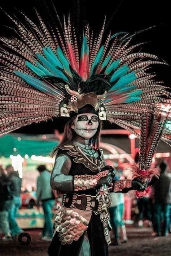20 La Catrina-Kostüme, einfaches Make-up im Gesicht mit Skelett-Design am Körper, hohes Stirnband aus blauen Federn, schwarzer Anzug mit indigenen Details
