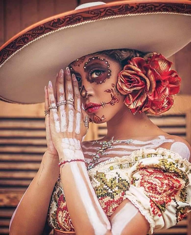 43 La Catrina-Kostüme, Make-up mit Cempasuchil-Blume in den Augen, Symbolen im Gesicht, Skelett am Körper, blumiges Kleid, Haare zusammengebunden mit traditionellem Hut und orangefarbener Blume auf einer Seite