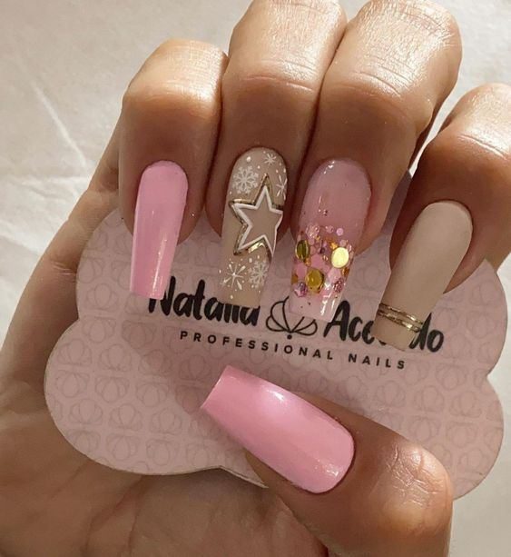 94 Nails with light beige enamel stars white and gold stars on pink ring finger on pinky fingers and nude thumb with sparkles on light beige middle finger and gold lines on index finger