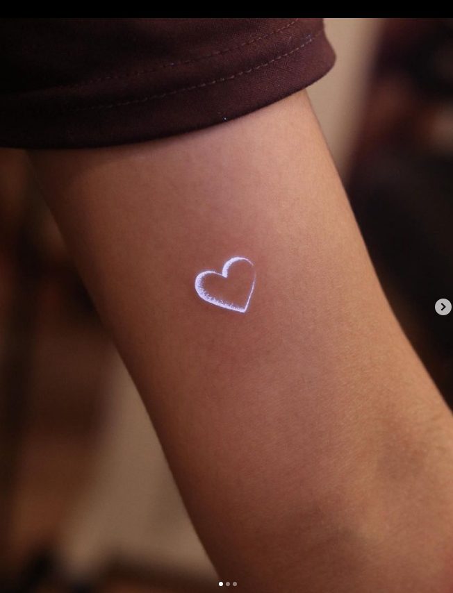 TOP4 mini heart in white ink that looks like a lunar eclipse on the arm