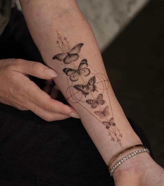 49 tatouages de la nature bras papillons alignés longitudinalement en noir avec des symboles astraux phases de la vie