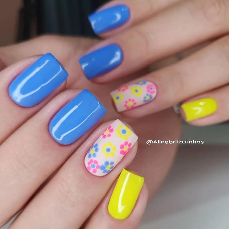5 designs de unhas quadradas curtas em tons de azul, amarelo e branco com desenhos simples de flores