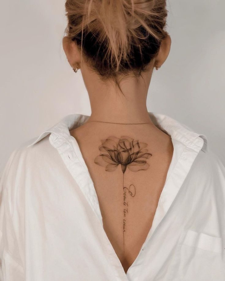 Tatuajes Elegantes Negros difuminado de flor con puntillismo en la parte alta de la espalda cuello y inscripcion