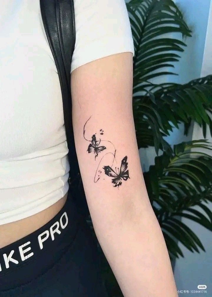 Tatuajes Elegantes Negros mariposas en antebrazo con manchas de tinta negra