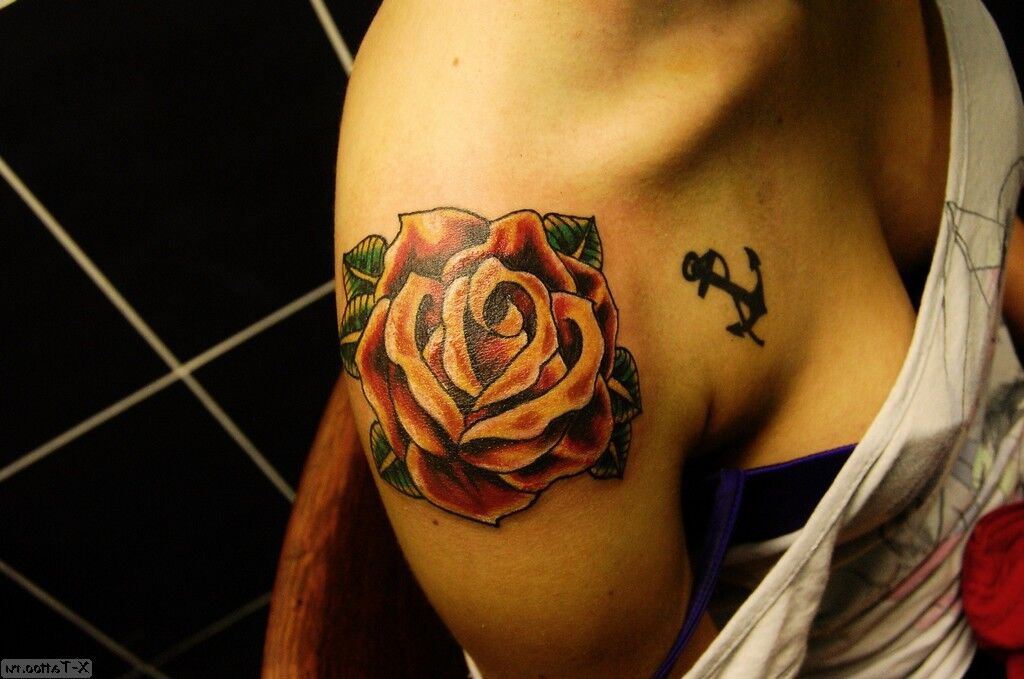 Tattoo Rose tattoo next to an anchor on shoulder