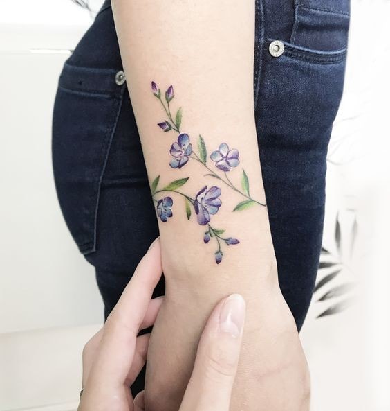 Flores e ramos no antebraço de uma mulher, pequena pulseira violeta tipo 16
