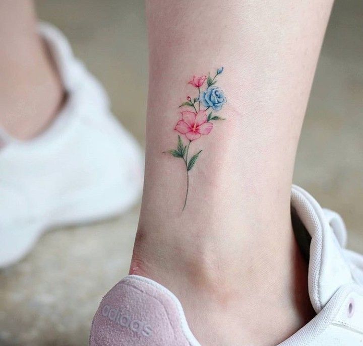 As mais belas e delicadas tatuagens para tornozelos um pequeno buquê colorido atrás de flores rosa e azuis