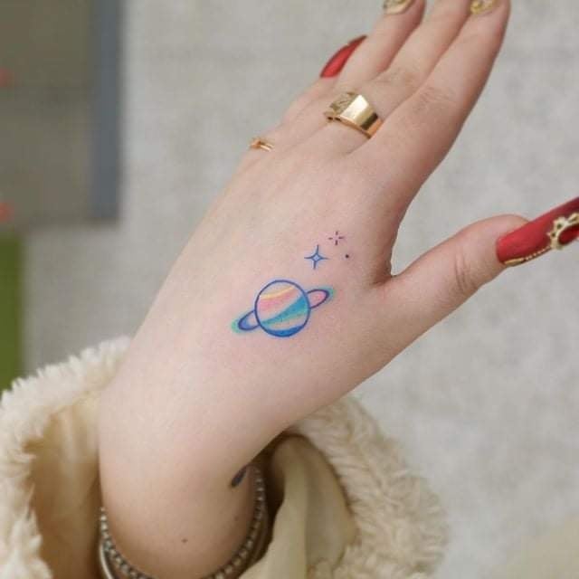 Kleines vollfarbiges Tattoo für Frauen Saturn und Sterne auf der Hand