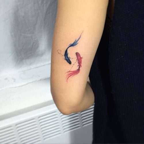 Petit tatouage en couleur pour les femmes deux poissons koi sur le bras bleu et rouge