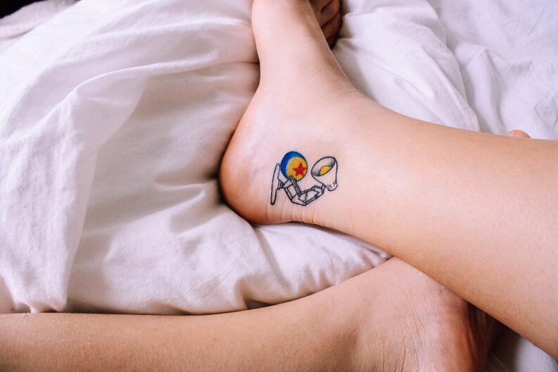 Kleines vollfarbiges Tattoo für Frauen mit abstraktem Motiv von Raumanzug und Lampe