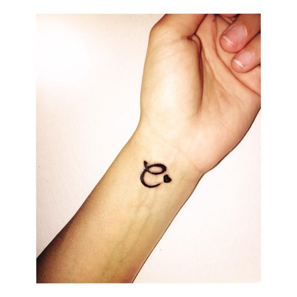 Tatuagem Letra C com pequeno coração preto no pulso