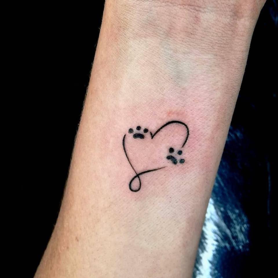 Petit tatouage à deux empreintes avec trois doigts et un cœur au poignet