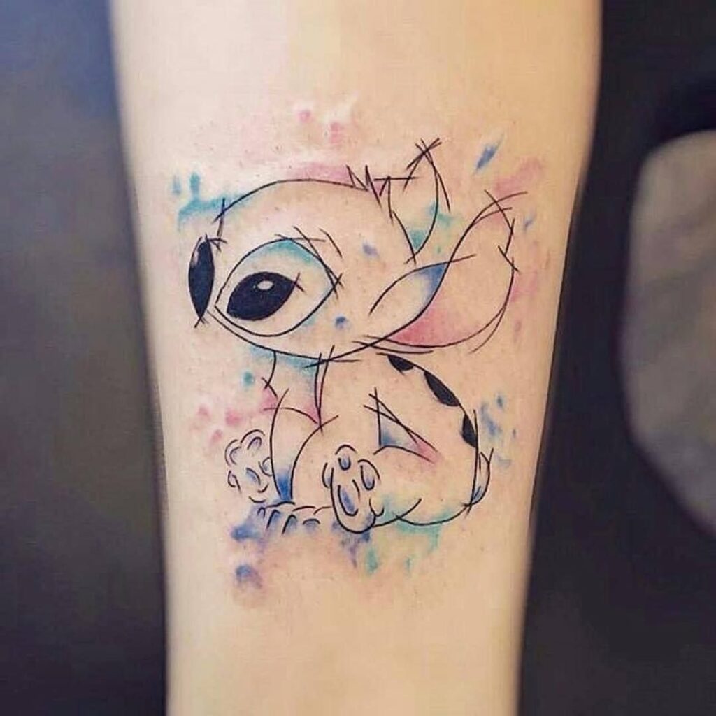Tatuaggio Stitch Ohana con contorni e tratti colorati sul braccio