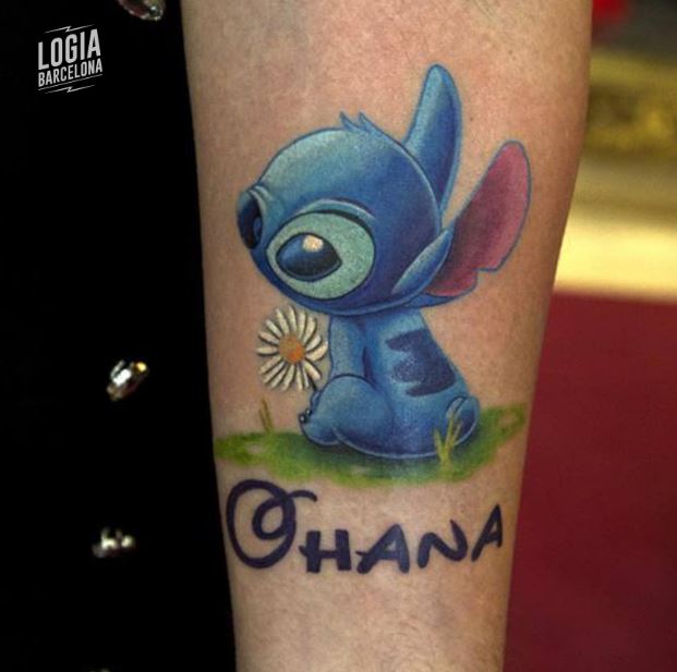 Stitch Ohana-Tattoo, das im Gras neben einer Gänseblümchenblume sitzt