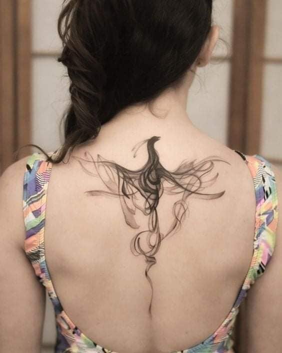 Smoke-type blurred Phoenix bird tattoo on woman's back and spine