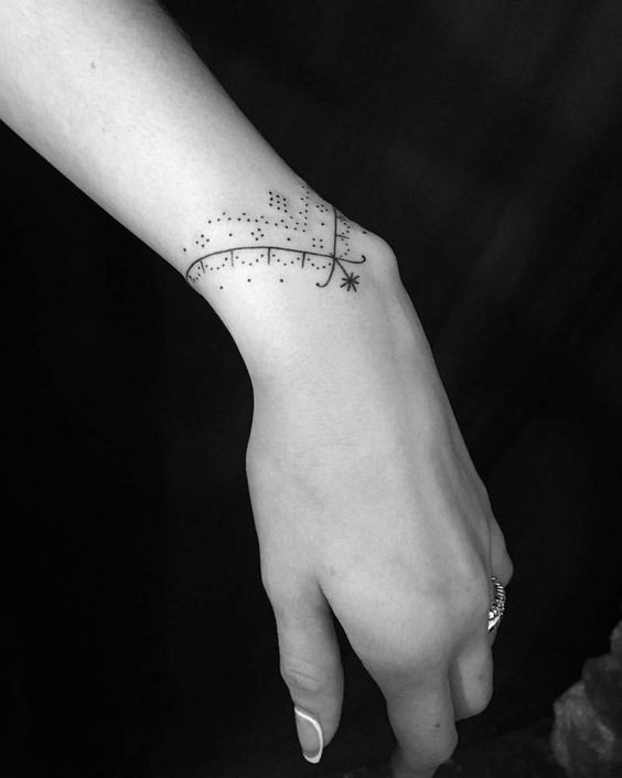 Bracciale o tatuaggio su bracciale, bellissimi dettagli sul polso e sulla mano, ornamento tipo girocollo triangolare con punti e linee sottili più stella all'estremità