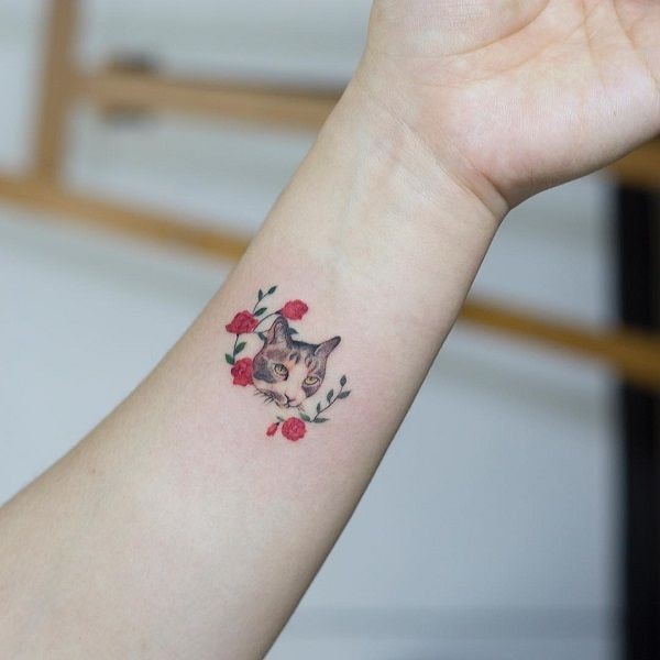 Gatto con fiori tatuati sul polso