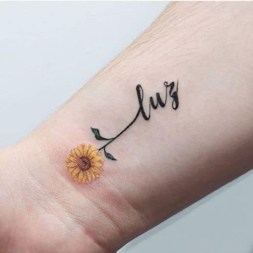 Kleines Sonnenblumen-Tattoo am Handgelenk mit der Aufschrift „Licht“.