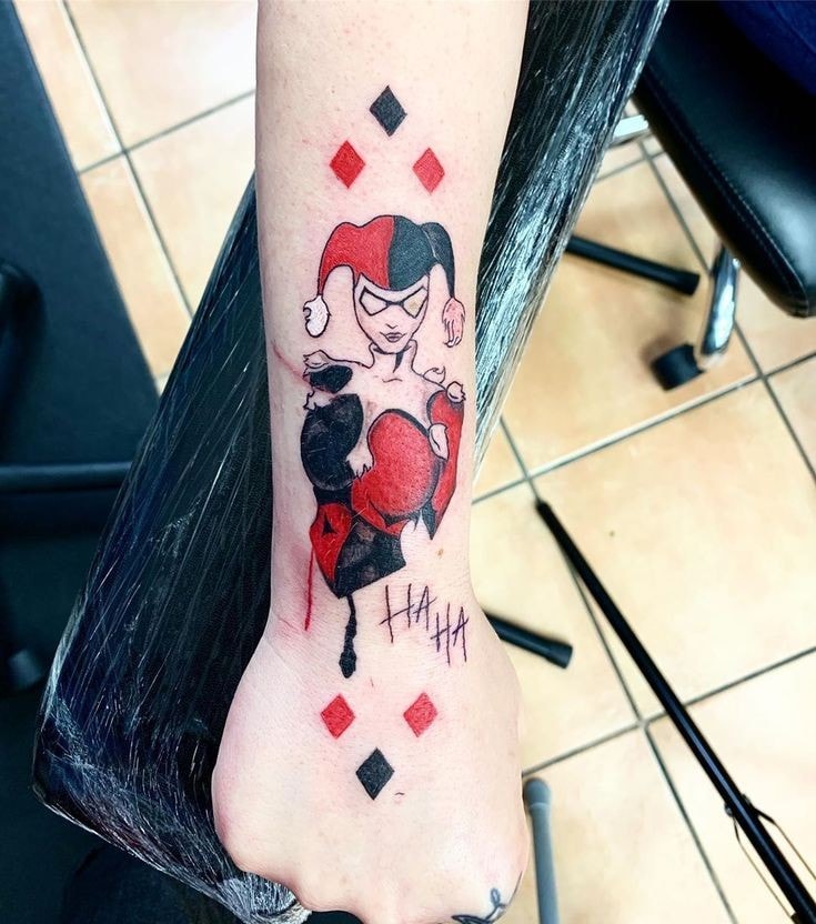 Tatuaje de Harley Quinn con rombos negros y rojos en antebrazo