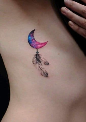 Tatuaje de Luna colores violeta y azul con plumas al costado del pecho