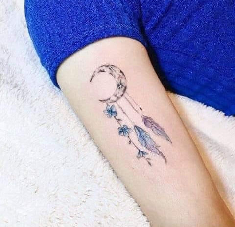 Tatuaggio lunare con acchiappasogni sul braccio