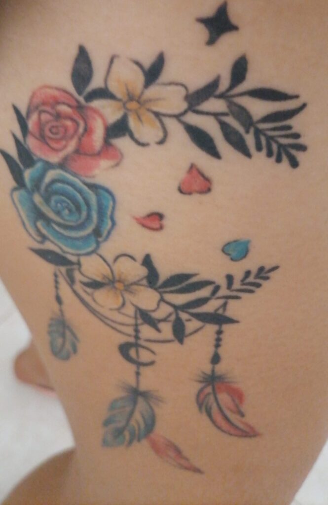 Moon tattoo with roses of various colors and feathers