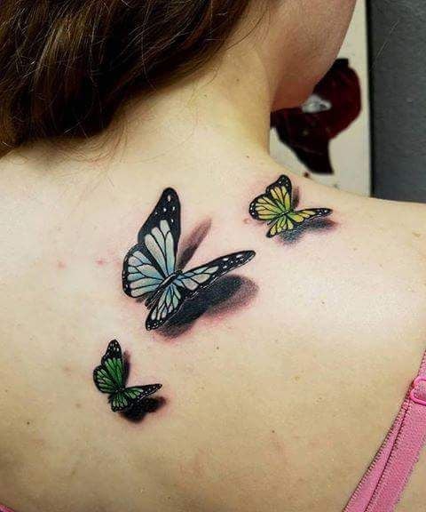 女性の背中と肩に 3 つの緑、青、オレンジの蝶の 3 D 蝶のタトゥー