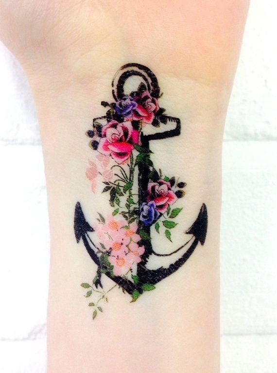 Tatuaje de ancla con flores en muneca de mujer
