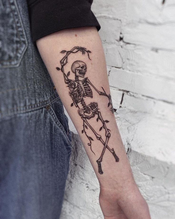 Tatuaje de esqueleto danzante con ramas en antebrazo