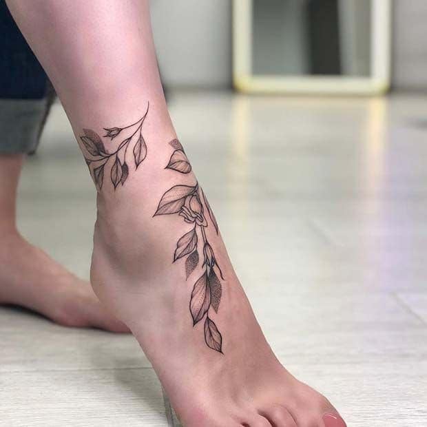 Tatuaje empeine mujer delicada rama y flores rodeando pie 40