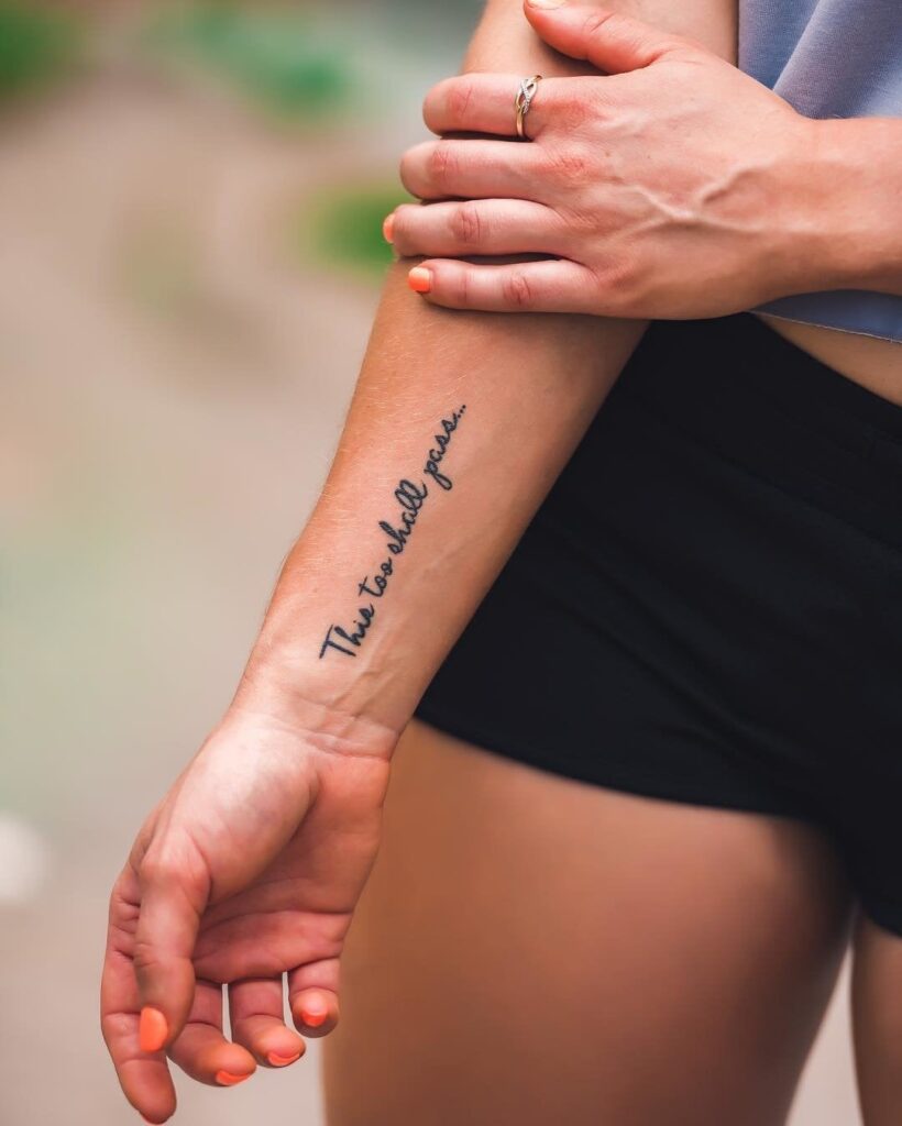 Tatuaggio sul polso di una donna con la scritta Anche questo passerà Anche questo passerà in inglese
