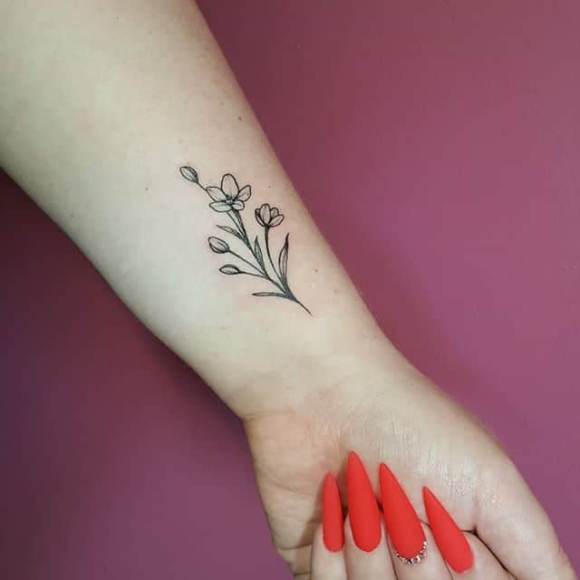 Tatuaggio sul polso di una donna con contorno di un mazzo di fiorellini