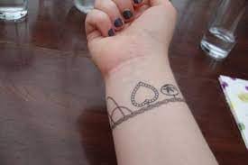Tatuaggio tipo braccialetto con cuori sul polso di una donna