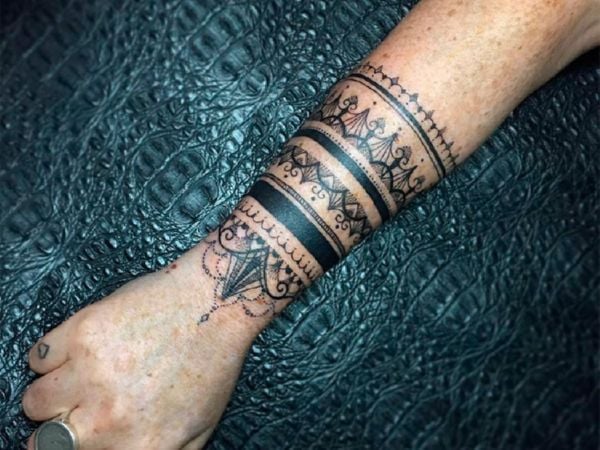 Tatuaggio di tipo tribale sul polso di una donna con un braccialetto molto largo