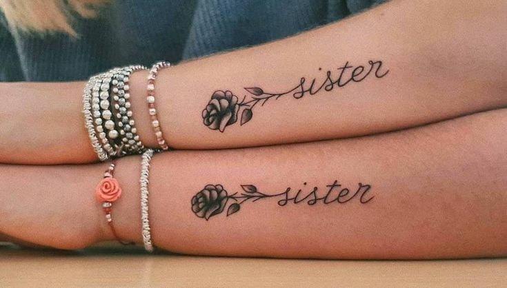 Il tatuaggio sull'avambraccio coppia la rosa nera e la parola sorelle