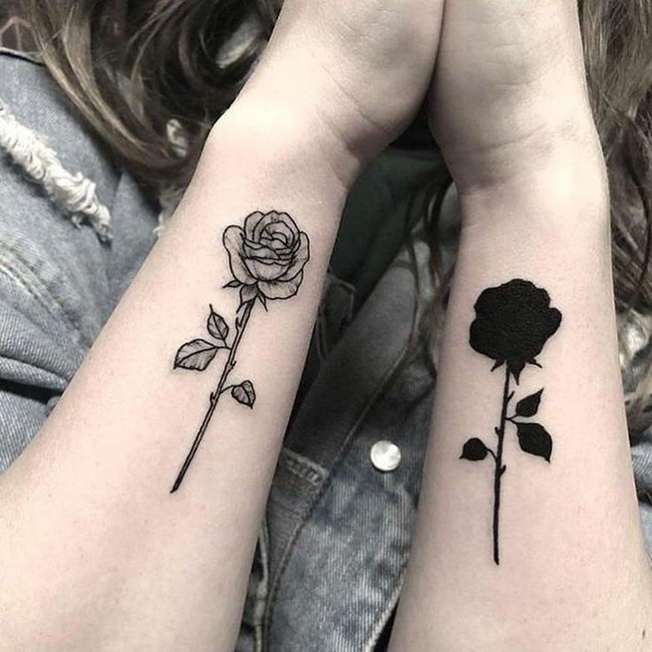 A tatuagem no antebraço combina uma rosa preta escura e outra rosa em contorno